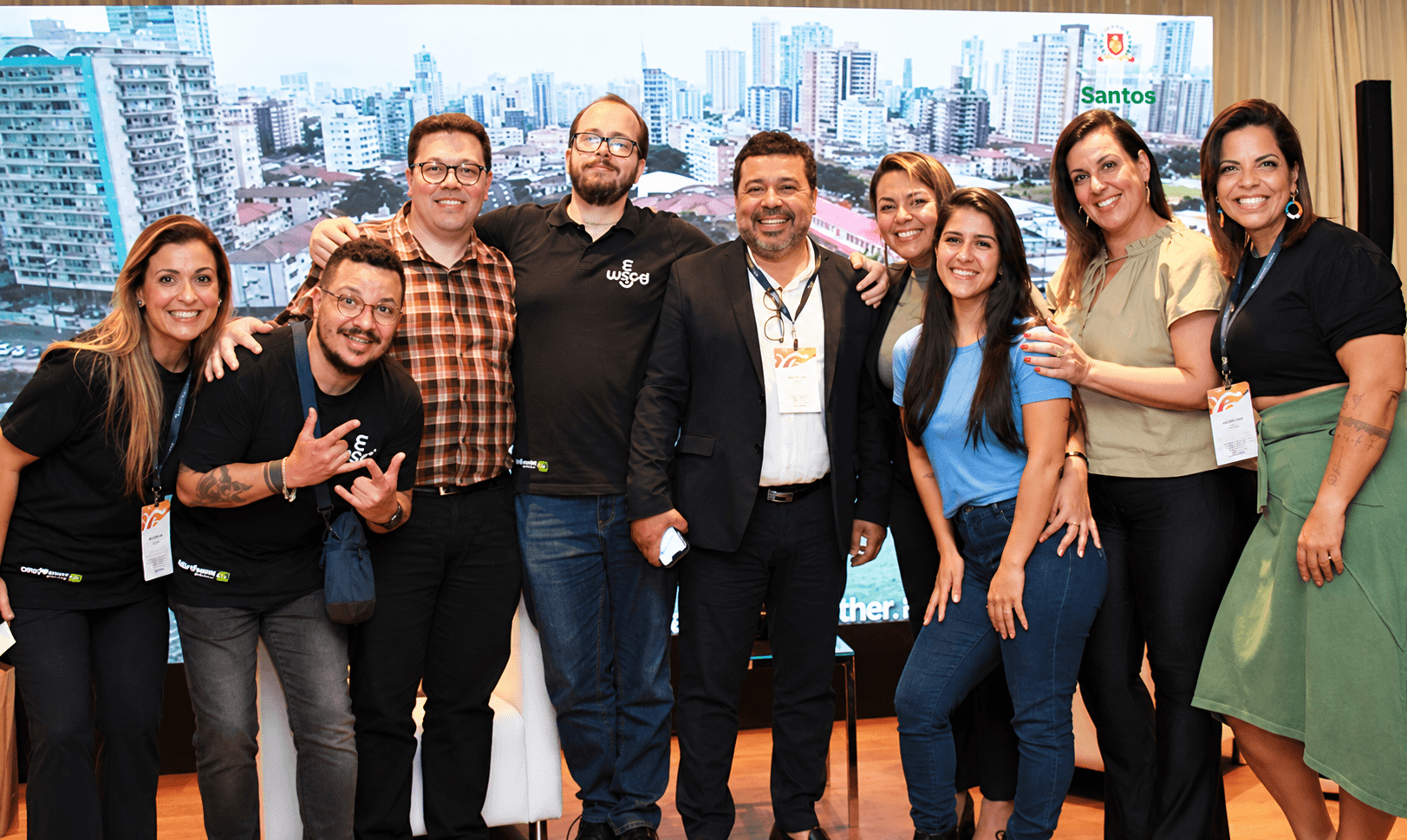 Equipe reunida diante de um painel com a cidade de Santos