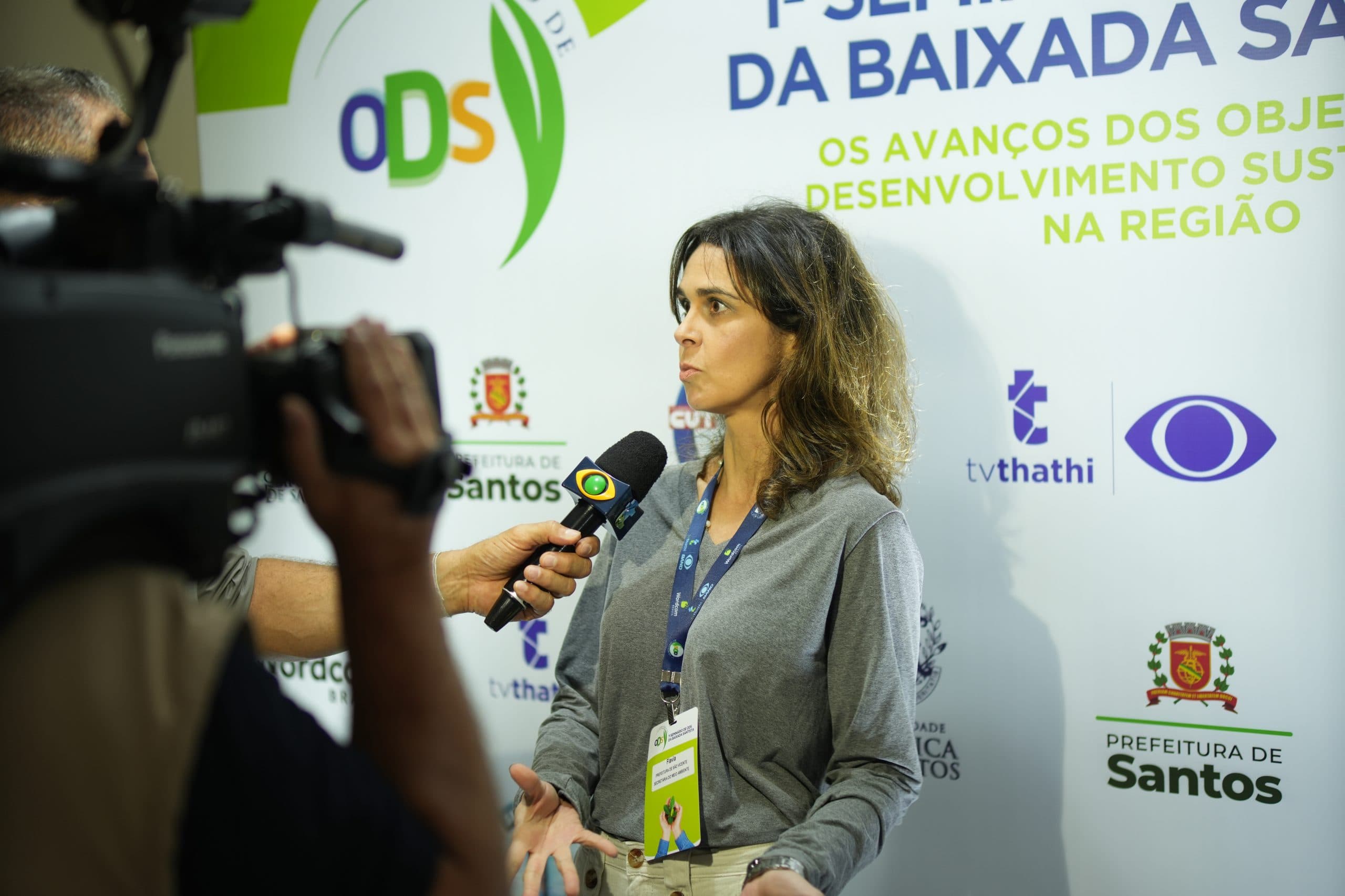 Entrevistada diante da identidade visual do Seminário de ODS
