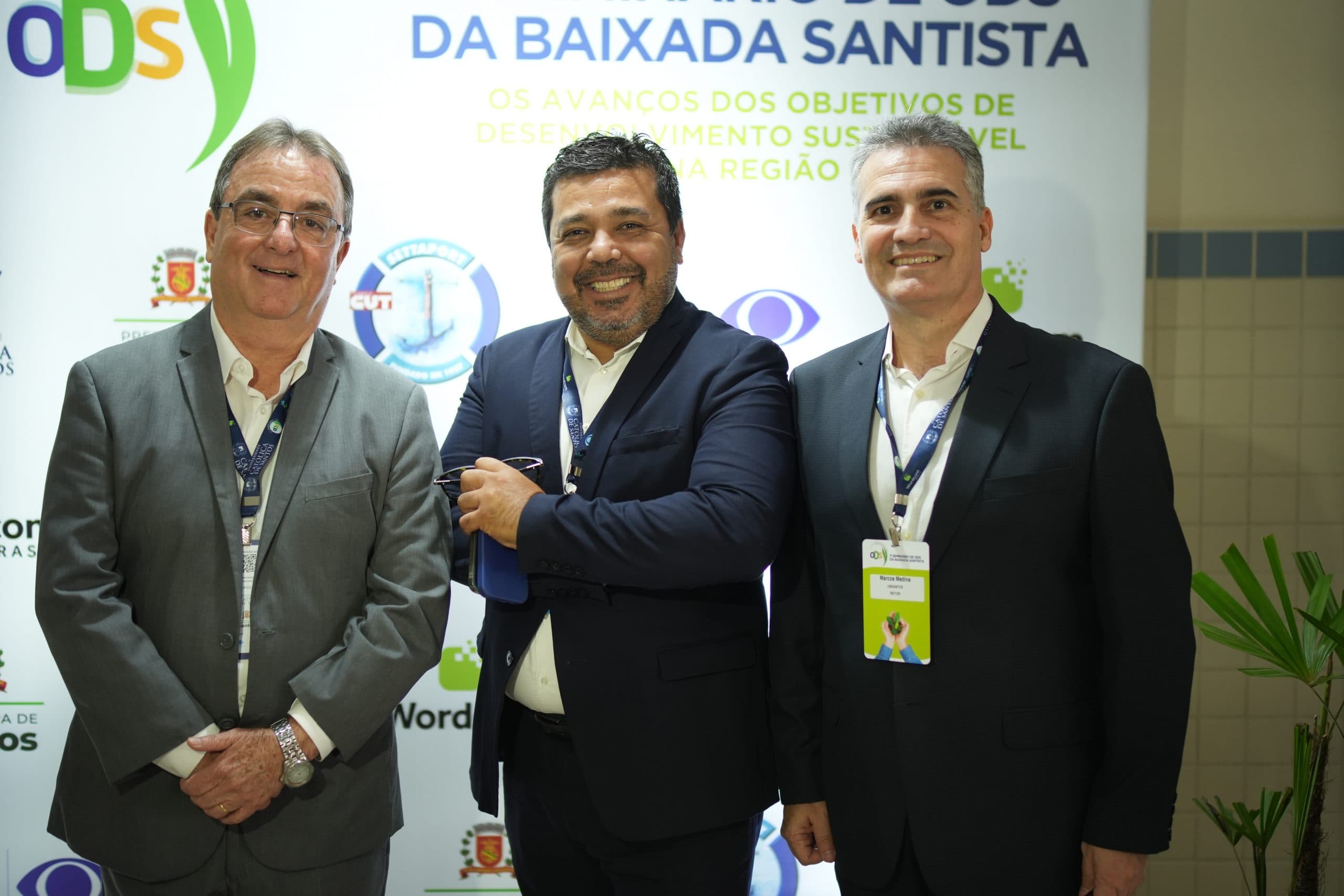 Três participantes diante do painel do Seminário de ODS da Baixada Santista