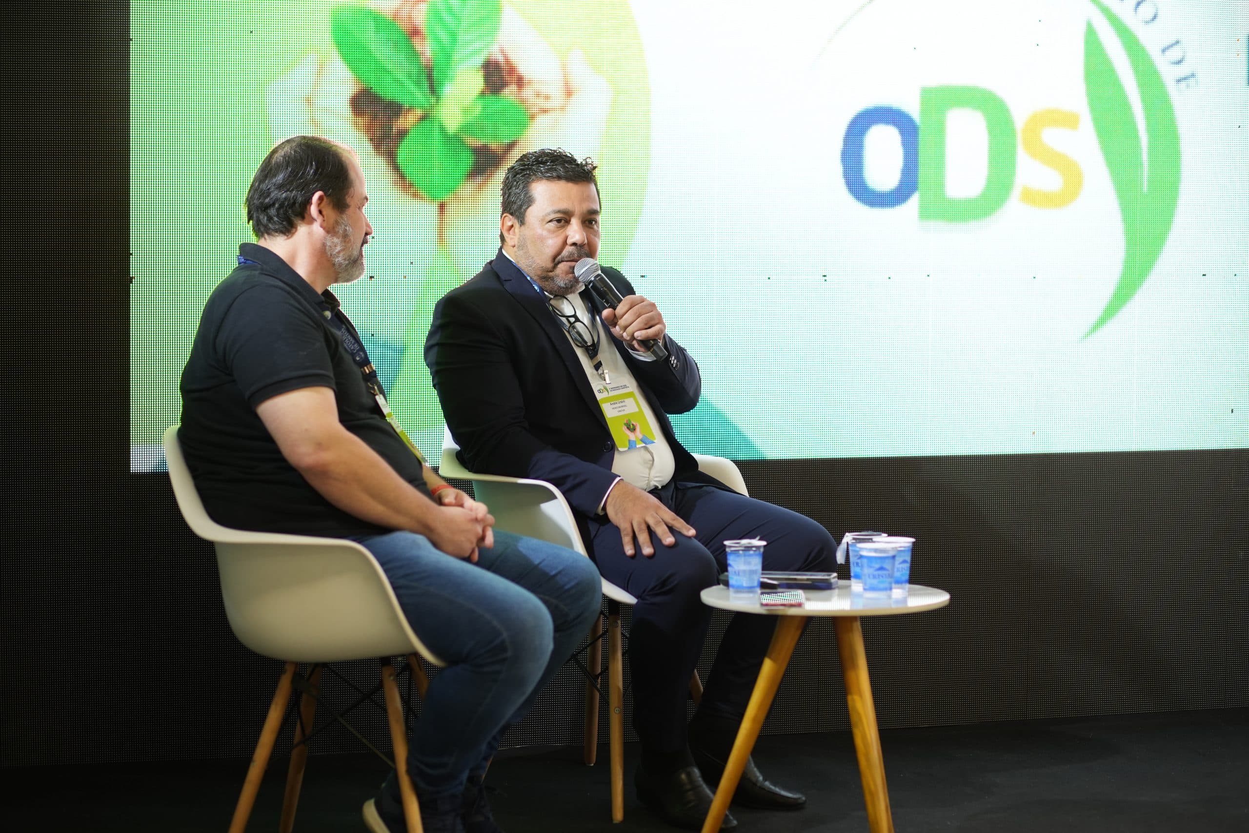 Participantes debatendo diante do telão com a marca ODS